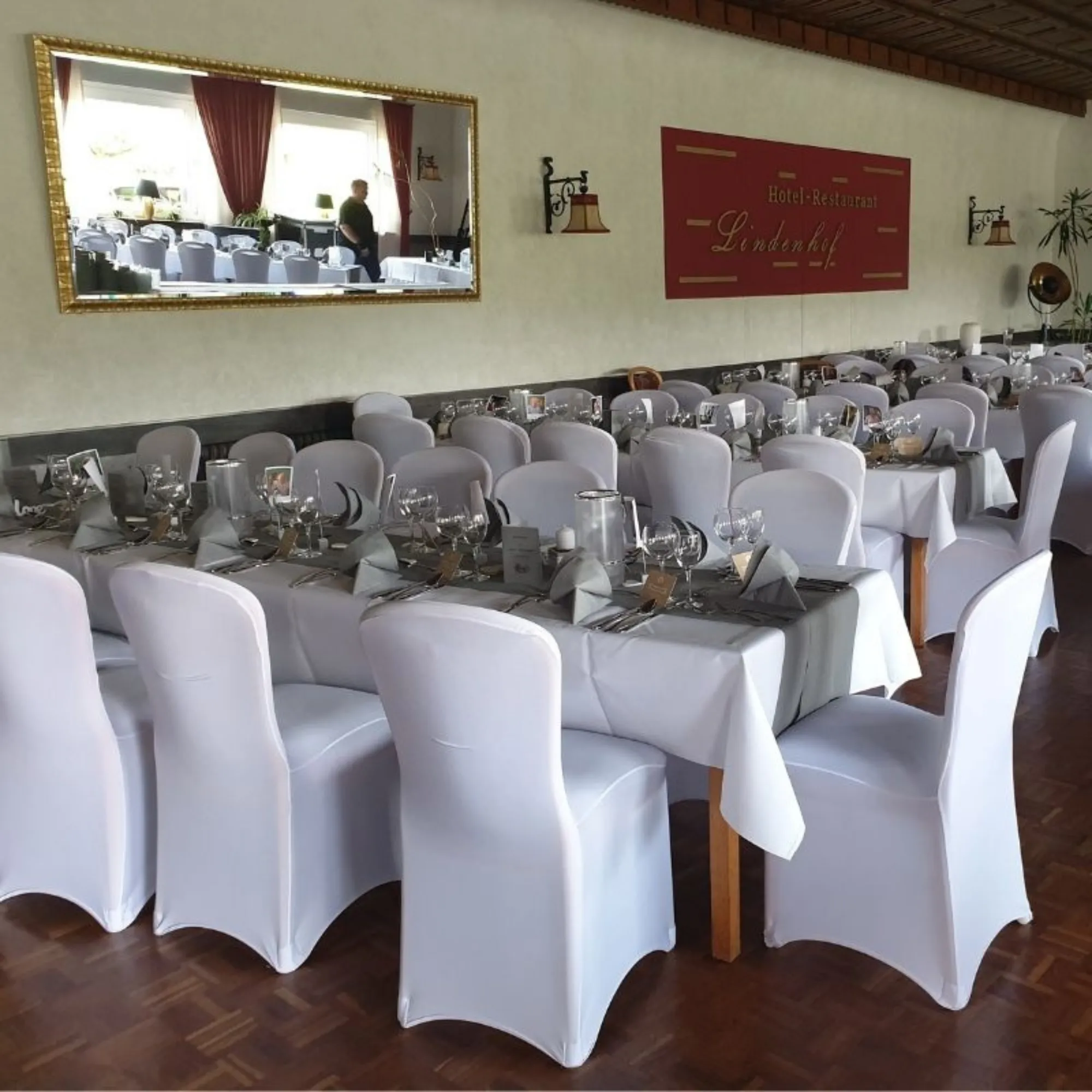 Stuhlhussen mieten in Osnabrück & Umgebung: Hochzeitssaal mit dekorierten Tischen und Stühlen mit weißen Hussen